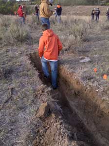 Contestant exiting shallow narrow pit in field.