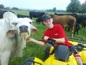 image of boy on tractor posing next to an animal